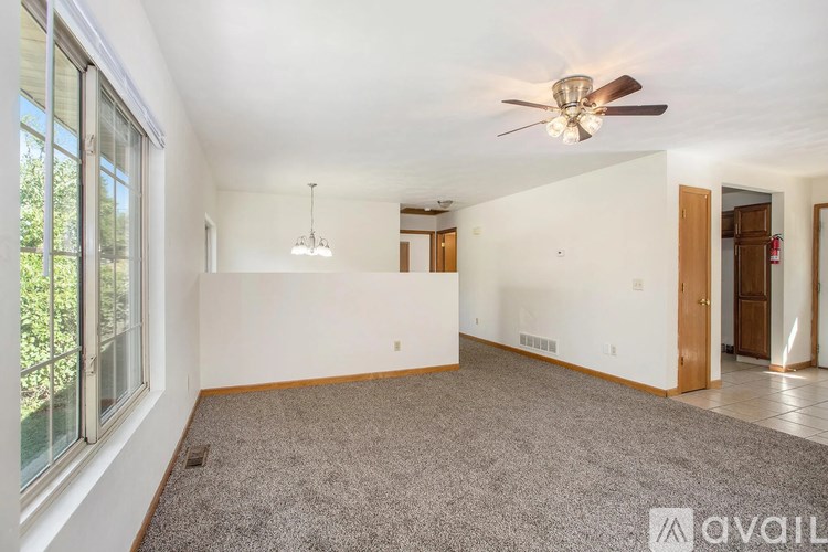 A spacious room with a ceiling fan and a carpeted floor.