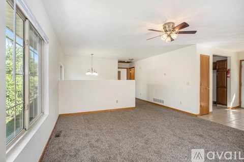 A spacious room with a ceiling fan and a carpeted floor.