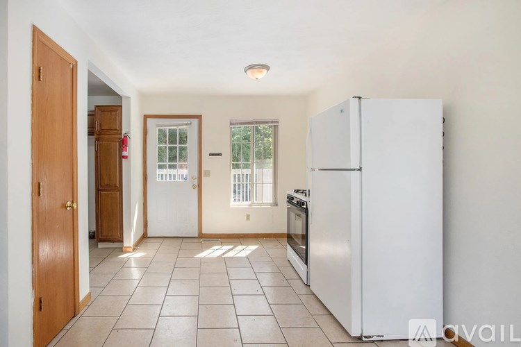 A kitchen with a refrigerator, oven, and a window.