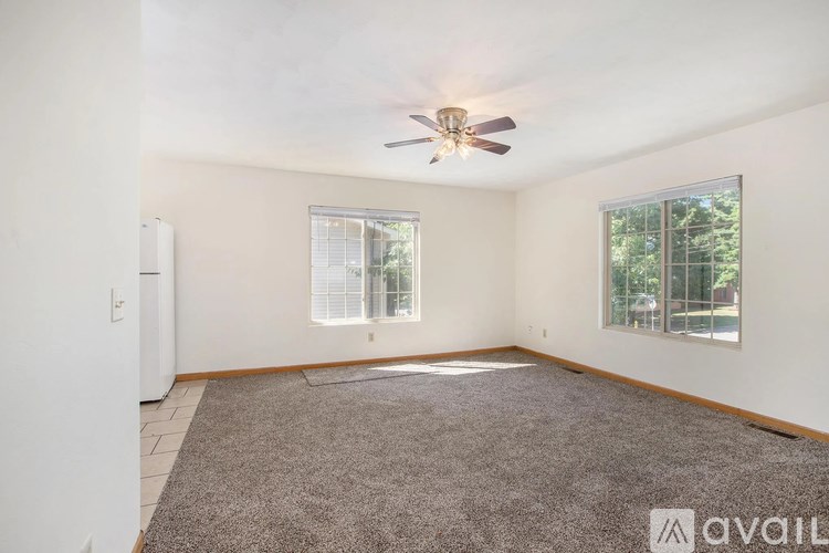 A room with a ceiling fan and two windows.