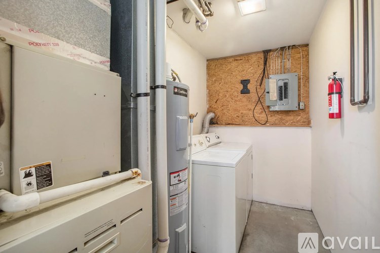 A small utility room with a washer and dryer, a water heater, and a fire extinguisher mounted on the wall.