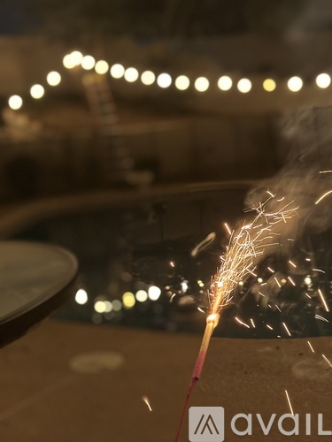 A sparkler is lit and burning with a blurry background.