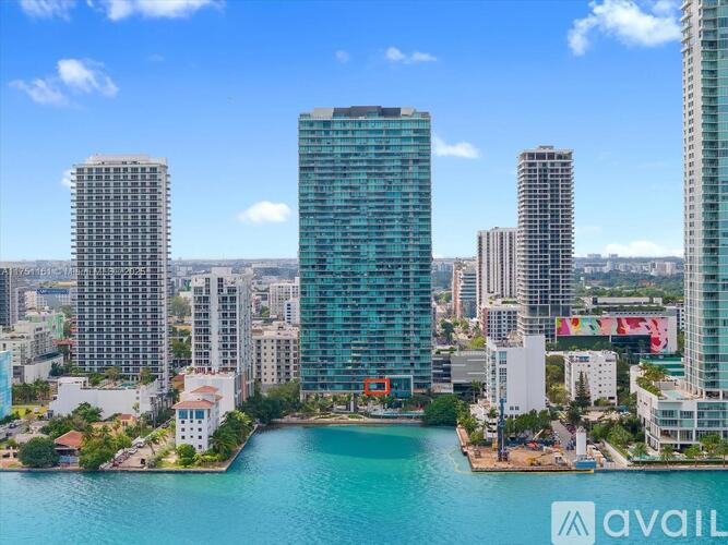 A cityscape with a body of water in the foreground and buildings of varying heights.
