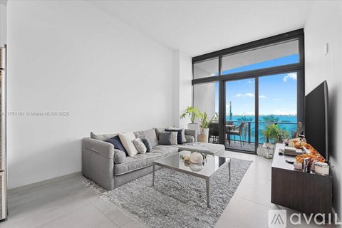 A modern living room with a grey sofa and a glass table.