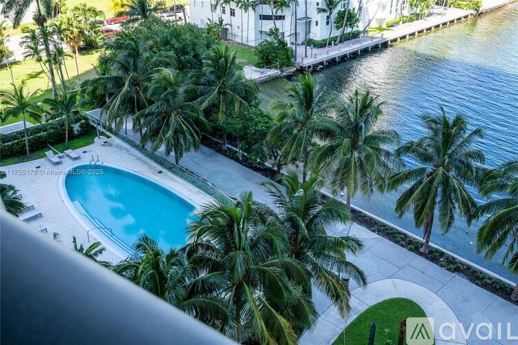 A pool surrounded by palm trees and a waterfront view.