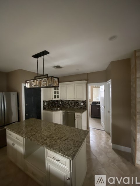 A kitchen with granite countertops and a hanging light fixture.