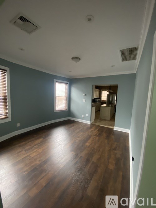 A room with wooden floors and a doorway leading to another room.