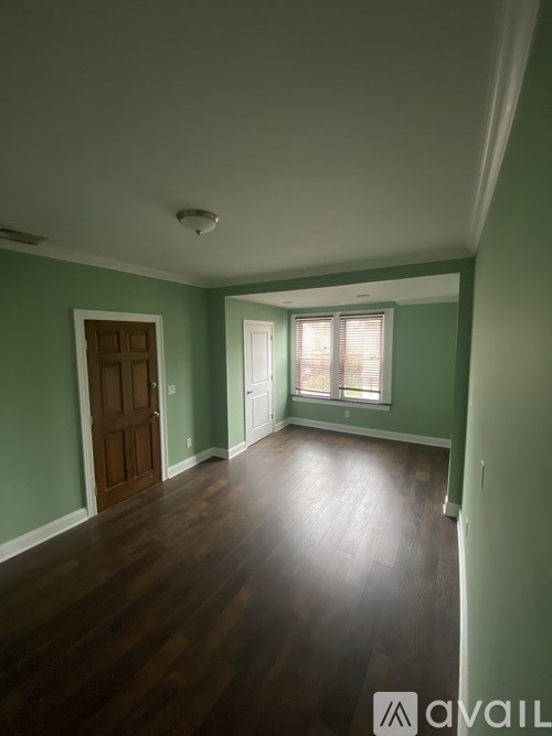 A room with a wooden floor and a window with blinds.