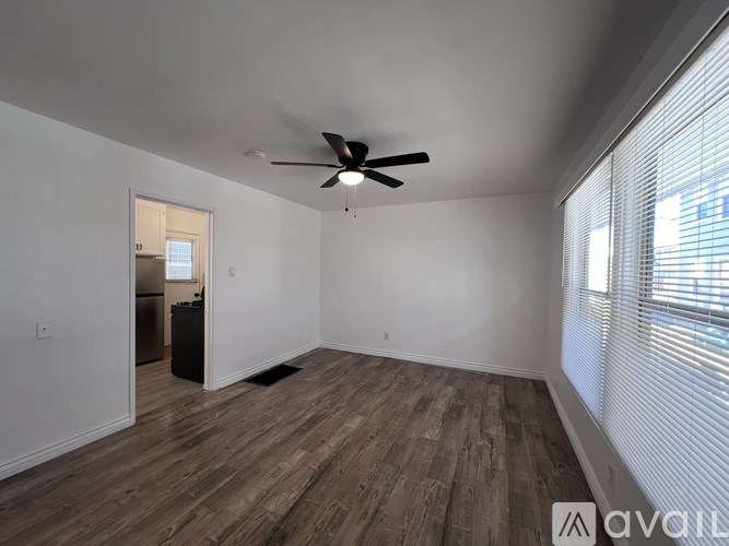A room with a ceiling fan and wooden flooring.