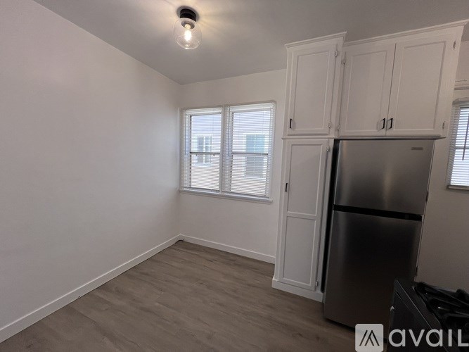 A kitchen with a refrigerator, cabinets, and a window.