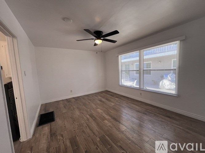 A room with a ceiling fan and a window overlooking a street.