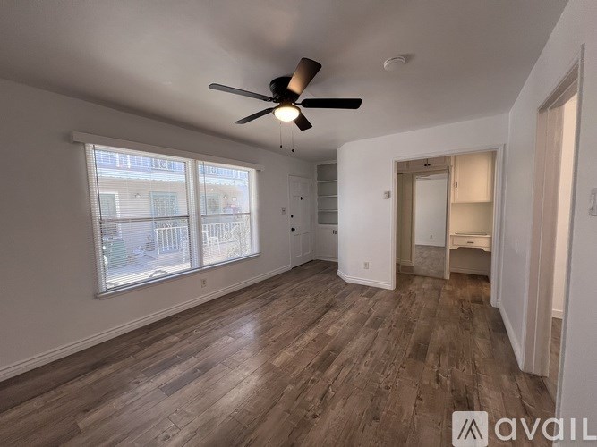 A room with a ceiling fan and wooden flooring.