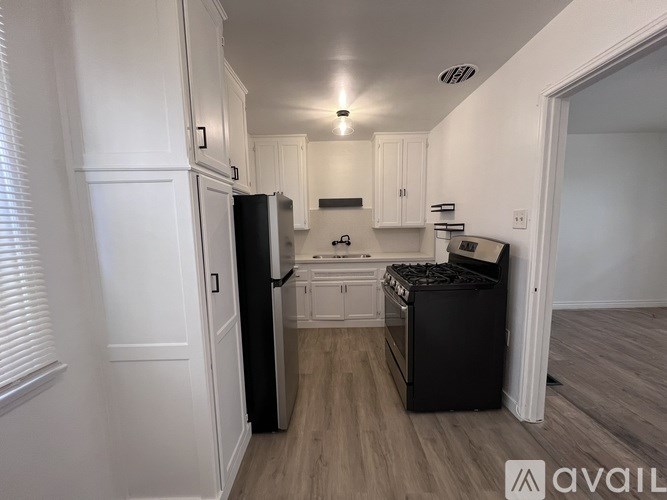 A kitchen with white cabinets and a black fridge.