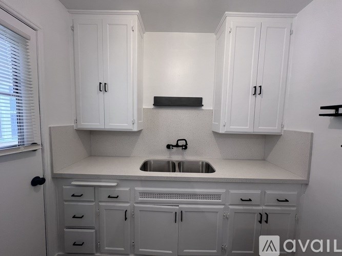 A white kitchen with a sink and cabinets.