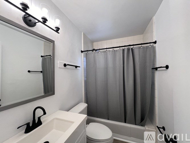 A white bathroom with a toilet, sink, and shower.