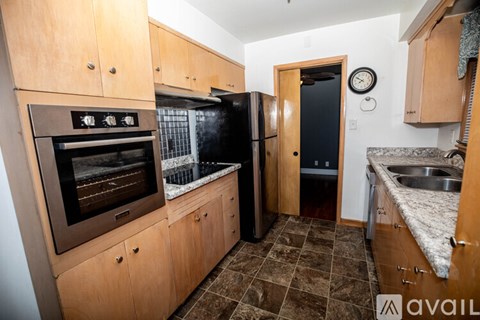 A kitchen with wooden cabinets and a black fridge.