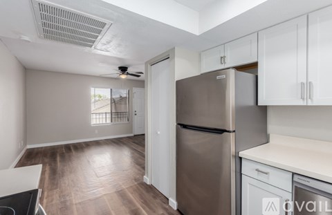 A kitchen with a refrigerator, stove, and cabinets.