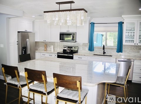 A kitchen with white cabinets and a marble countertop.