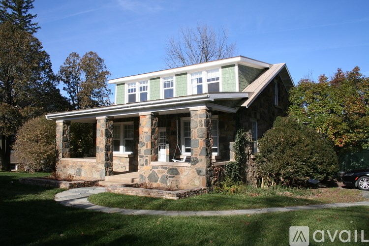 A house with a green roof and stone pillars is for sale.