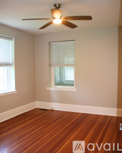 A room with a ceiling fan and wooden flooring.
