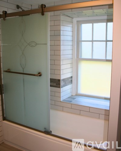 A bathroom with a glass shower door and a window.