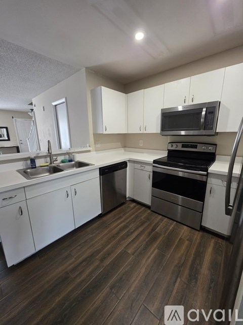 A kitchen with white cabinets and a wooden floor.