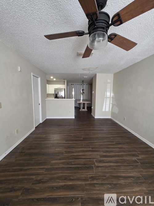 A room with a ceiling fan and wooden flooring.