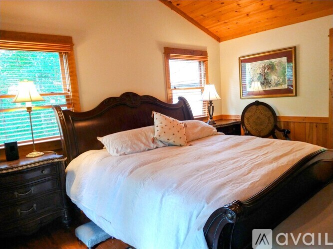 A bedroom with a large bed and a wooden ceiling.