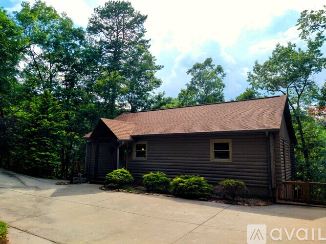 A house with a brown roof is surrounded by green trees.