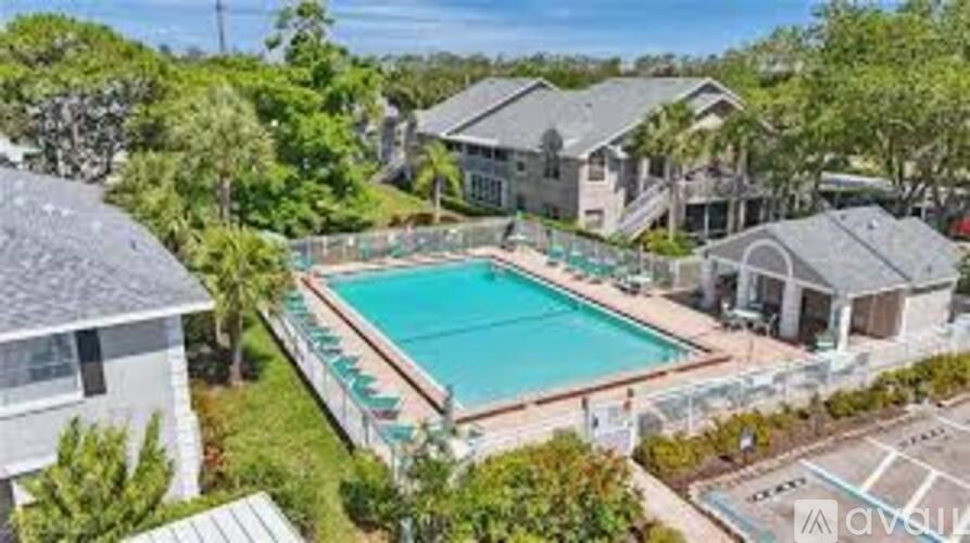 A swimming pool surrounded by a grassy area and a few trees.