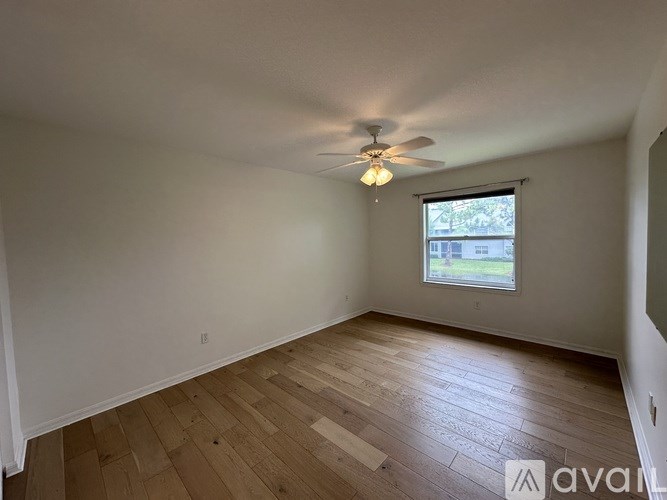 A bedroom with a bed, a fan, and a window with curtains.