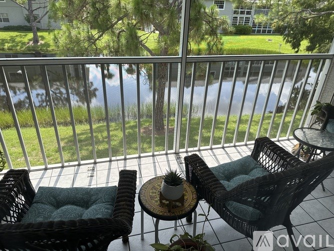 Two chairs and a table on a balcony with a view of the street.