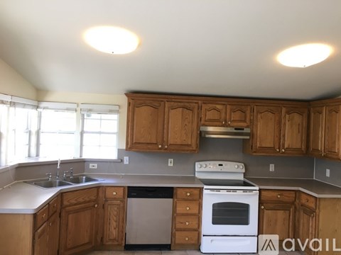A kitchen with wooden cabinets and a white stove top oven.