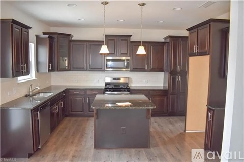 A kitchen with dark brown cabinets and a granite countertop.
