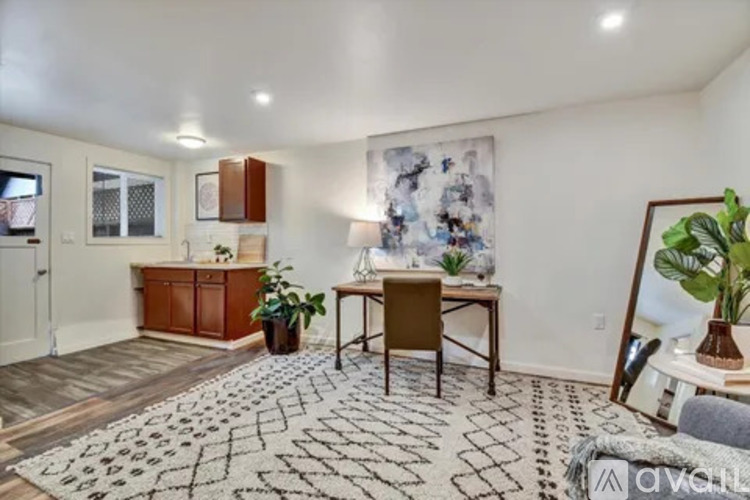 A room with a patterned carpet, a wooden desk, and a brown chair.