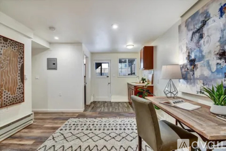 A room with a desk, chair, and a large painting on the wall.