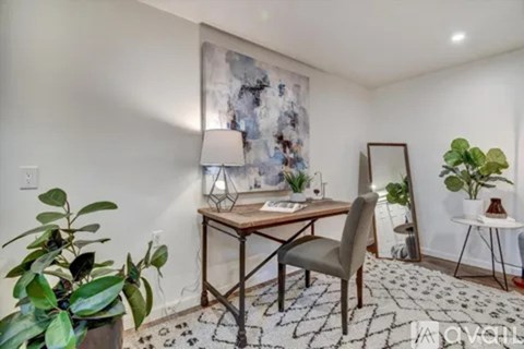 A room with a desk, chair, and potted plants.