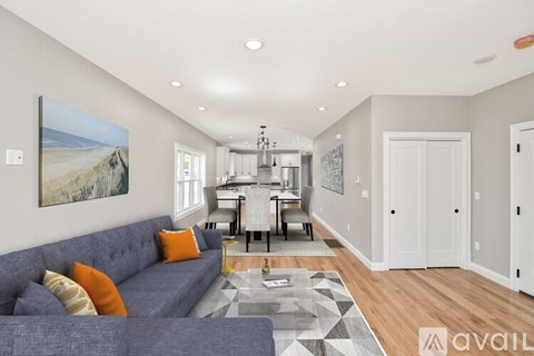 A living room with a grey couch and a painting of a beach scene on the wall.
