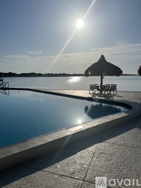 A sunny day at the pool with a sun umbrella and chairs.