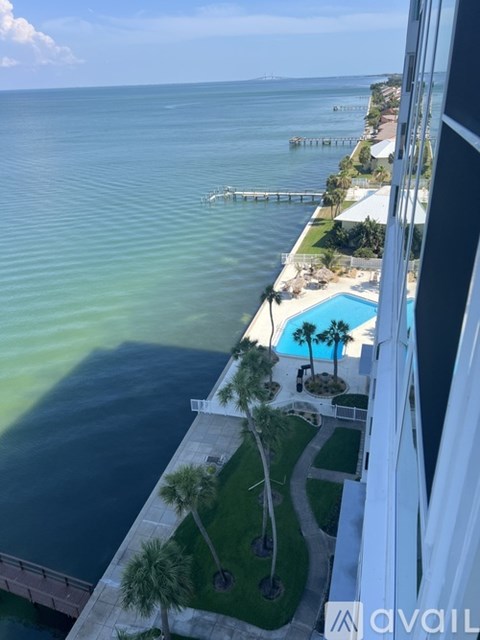 A view from a high-rise building overlooking a pool and a calm body of water.