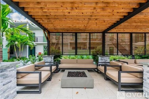 A wooden patio with a stone fire pit and four chairs.