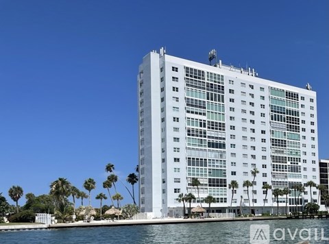 A tall building with many windows is surrounded by palm trees.