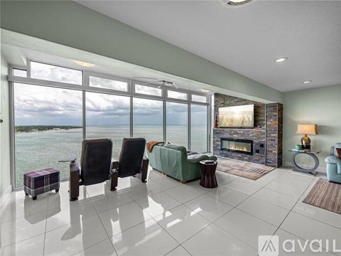 A living room with a view of the water and a fireplace.