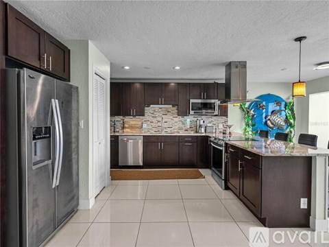 A kitchen with a refrigerator on the left and a counter with a mural on the right.