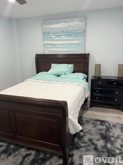 A bedroom with a bed, dresser, and a painting on the wall.