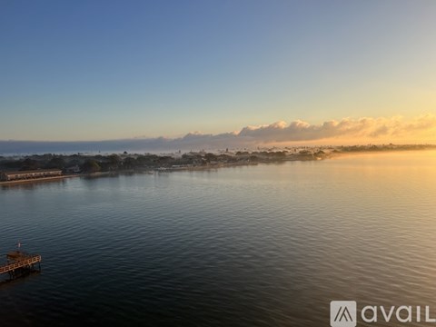 A serene body of water with a dock and mountains in the distance.