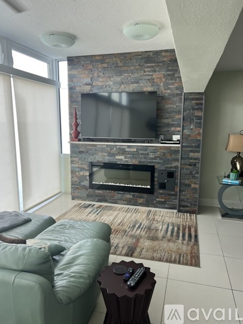 A living room with a stone fireplace and a grey couch.