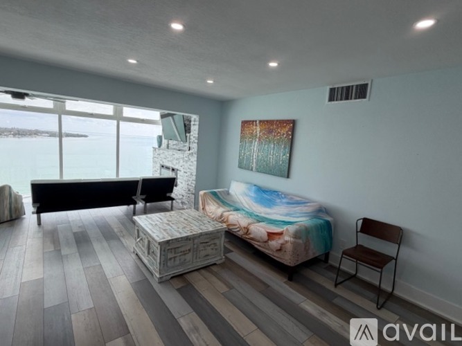 A bedroom with a large bed and a painting of a beach on the wall.