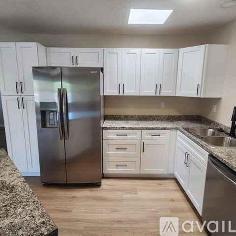 A kitchen with a stainless steel refrigerator and white cabinets.