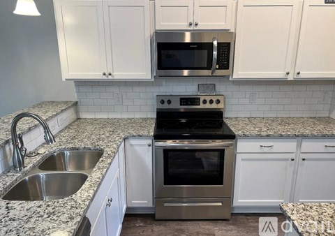 A kitchen with white cabinets and a granite countertop.